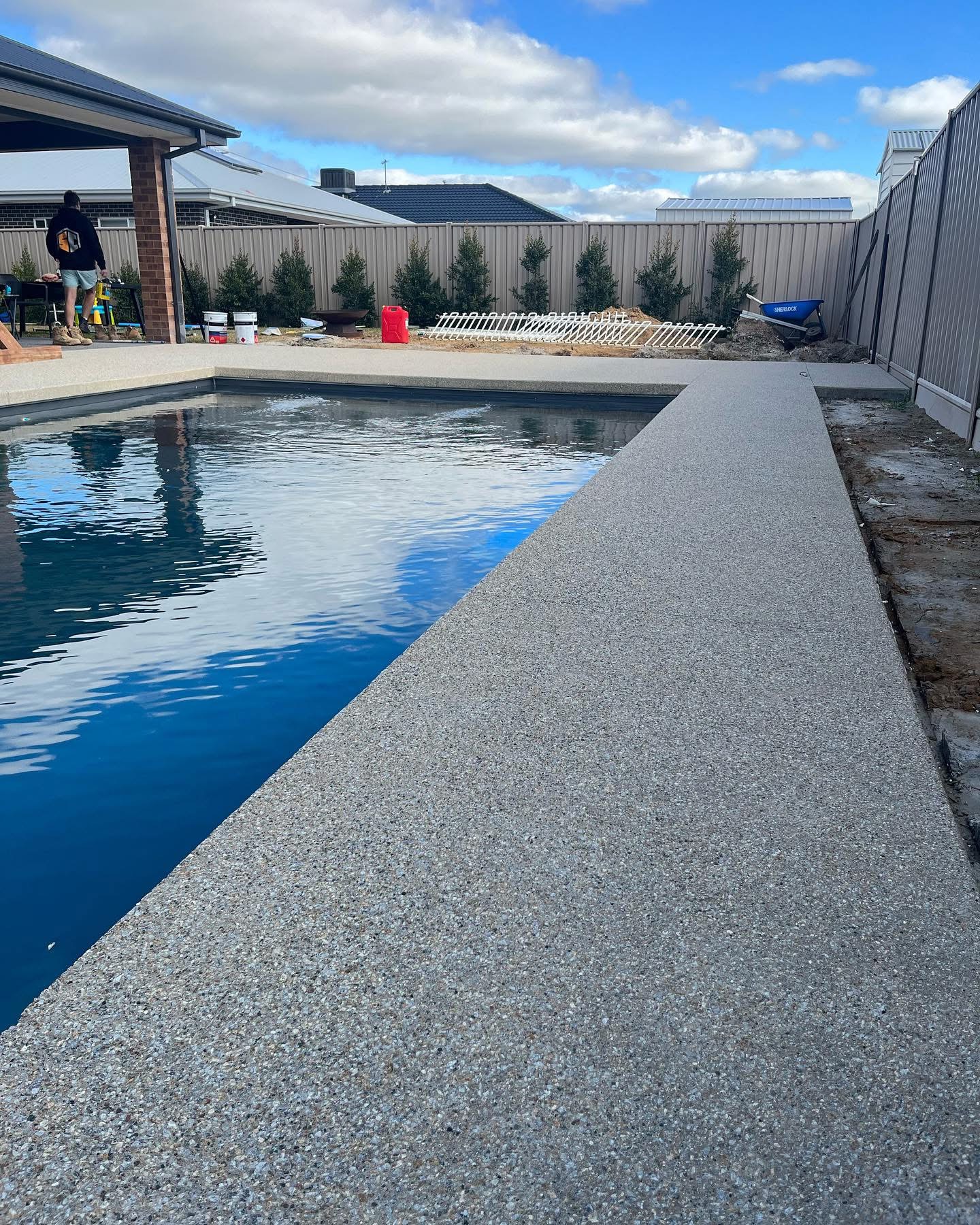 Seamless edge exposed aggregate pool surround poured flush to the water's edge with no coping