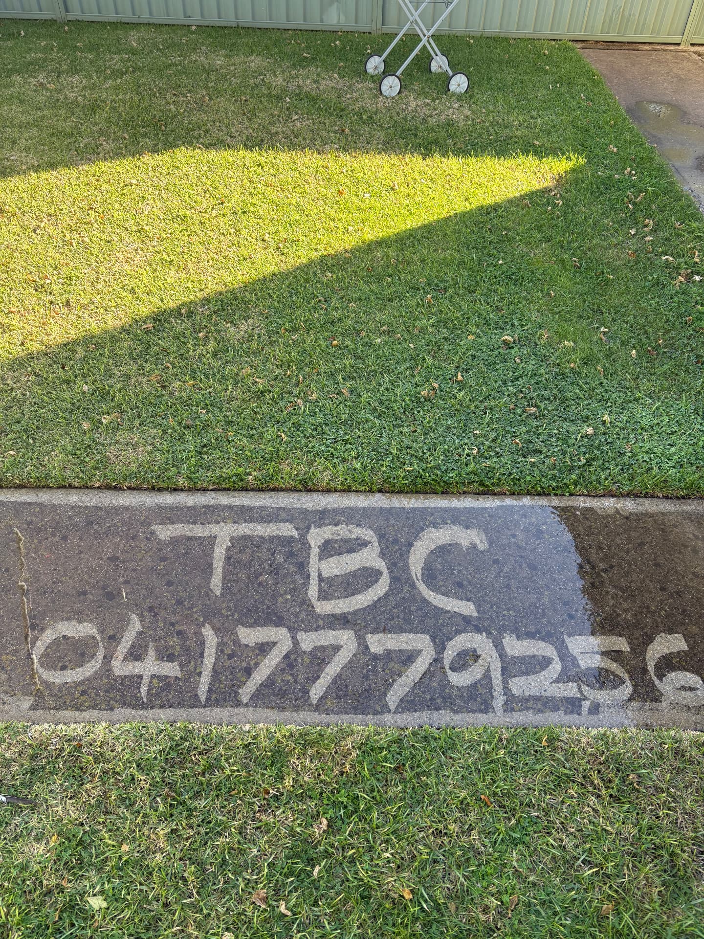 Pressure-cleaned concrete path showing TBC branding and phone number, demonstrating concrete cleaning results