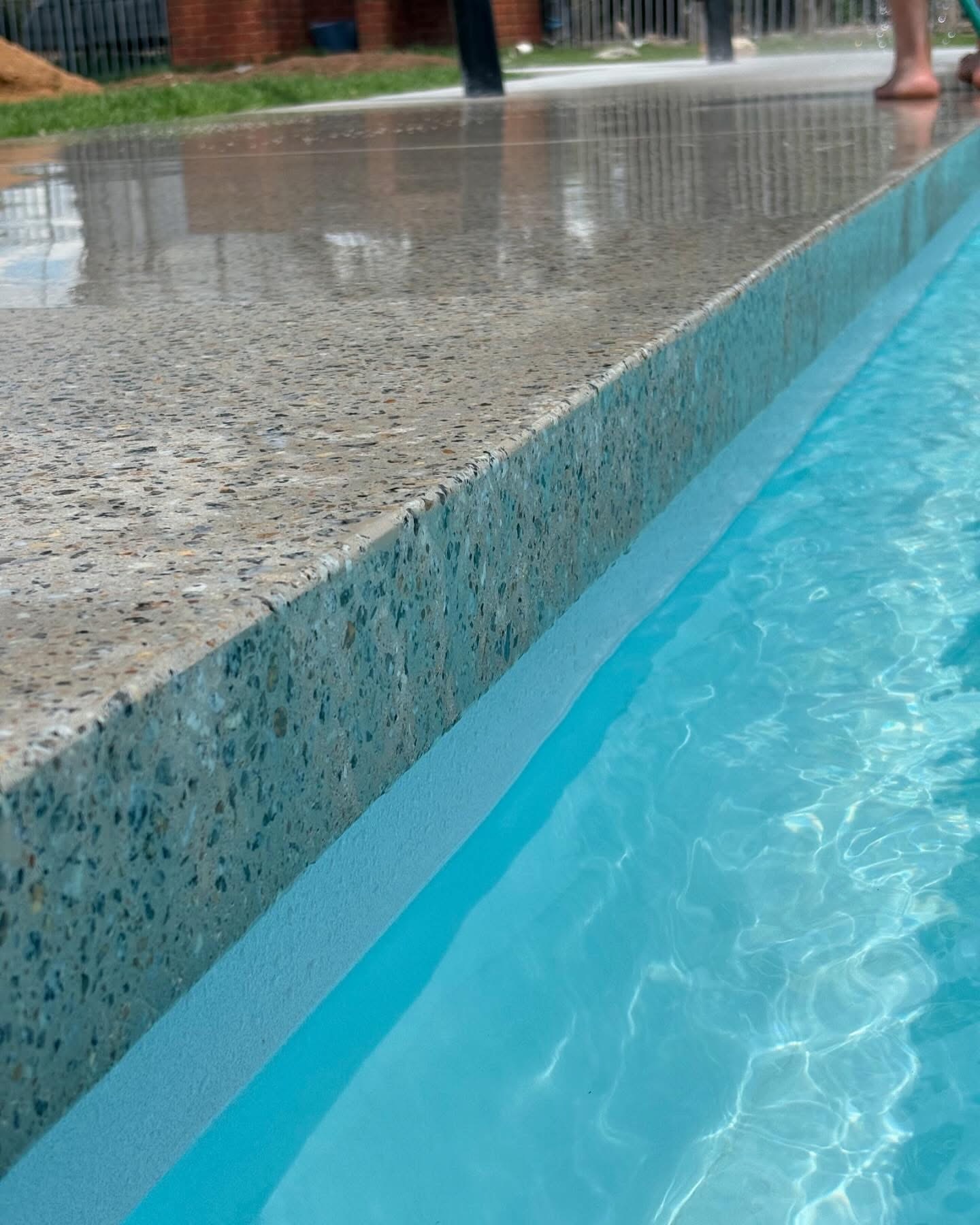 Close-up of a seamless edge polished concrete pool surround finished flush to the water